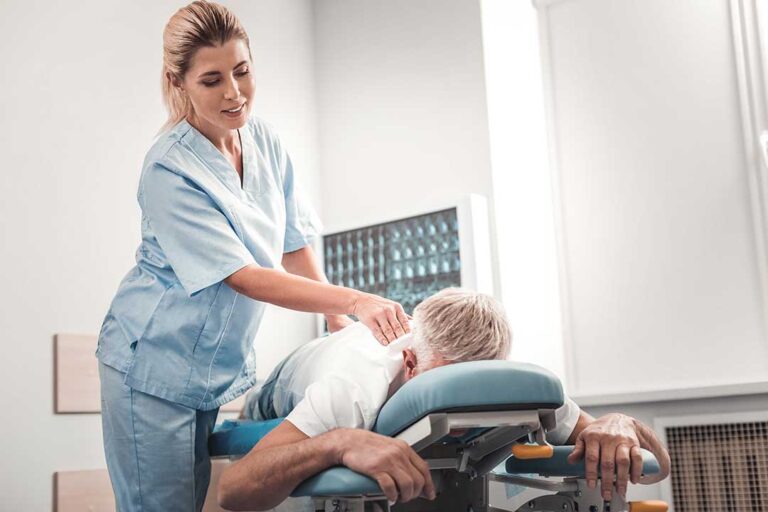 Chiropractor explaining spinal health with model spine to an attentive adult patient in a clinic.