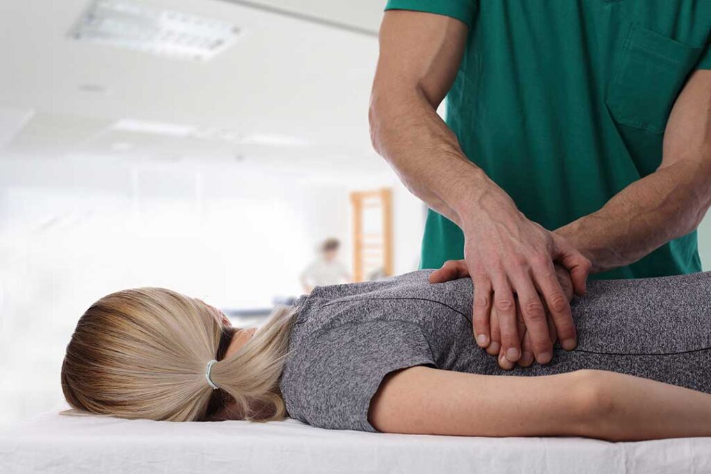 A chiropractor demonstrating gentle adjustment techniques on a smiling young child with a parent nearby.