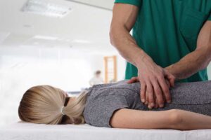 A chiropractor demonstrating gentle adjustment techniques on a smiling young child with a parent nearby.