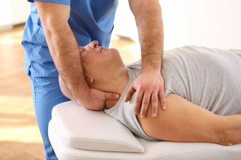 A chiropractor speaking gently to a patient while reviewing health forms in a comfortable office setting.
