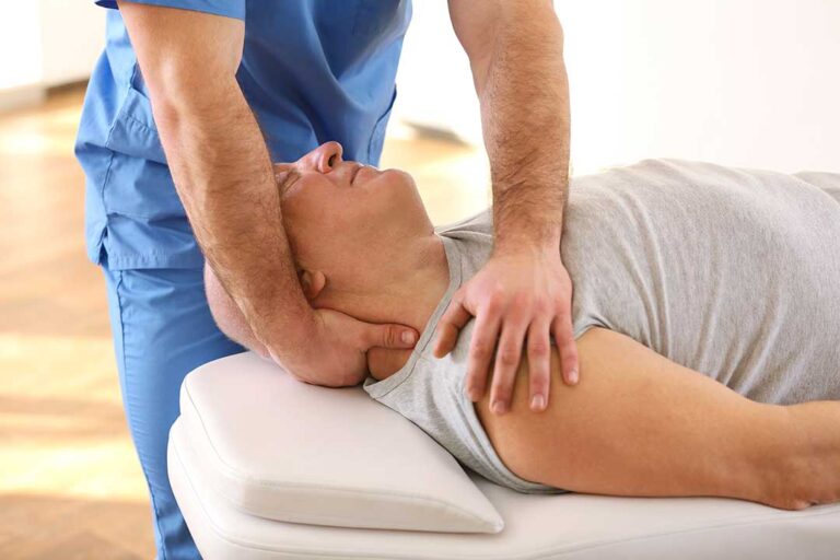 A chiropractor speaking gently to a patient while reviewing health forms in a comfortable office setting.